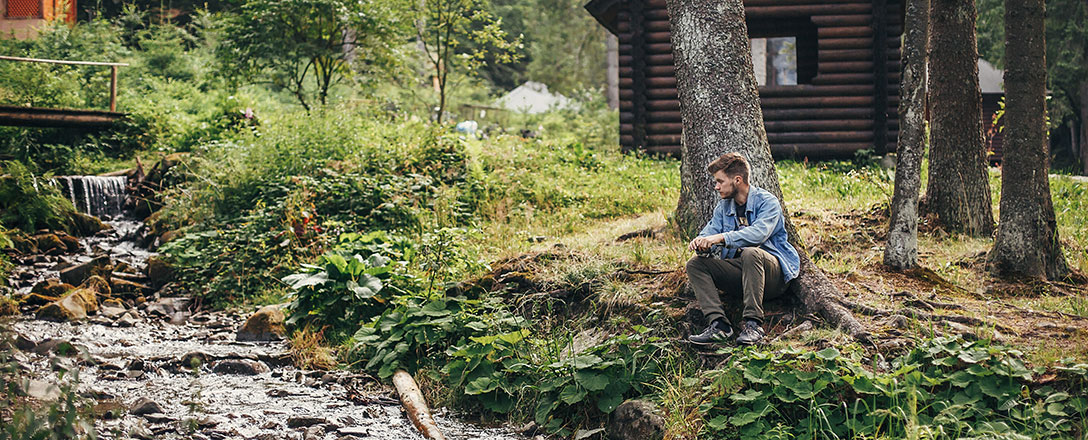 Mann entspannt bei Bach während nachhaltigem Hütten-Urlaub