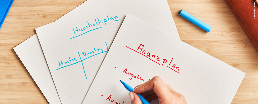 Hand mit Stift über Zettel für Finanz- und Haushaltsplanung