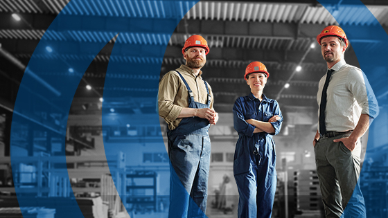 Drei Personen mit Helm in Werkshalle