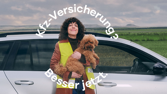 Frau mit Hund steht vor ihrem Auto.