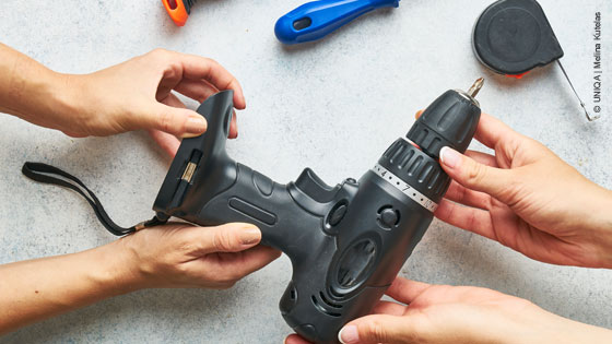 Hände überreichen eine Bohrmaschine