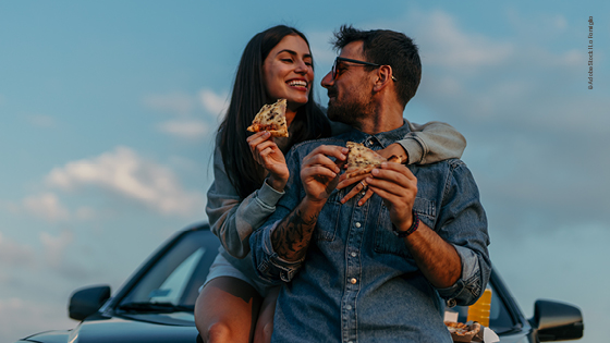 Mann und Frau essen beim Roadtrip Pizza