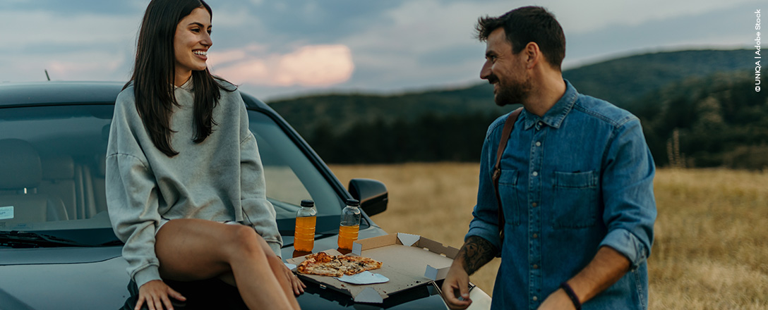 Mann und Frau sitzen auf ihrem Auto während ihres Roadtrips