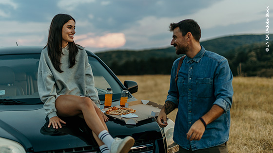 Mann und Frau sitzen auf ihrem Auto während ihres Roadtrips
