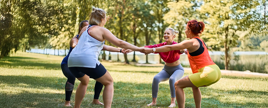 Gruppe von Freund:innen bewegt sich gemeinsam im Sommer draußen