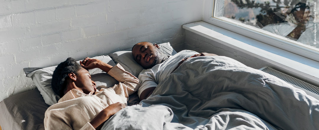 Paar liegt im Winter gemeinsam im Bett