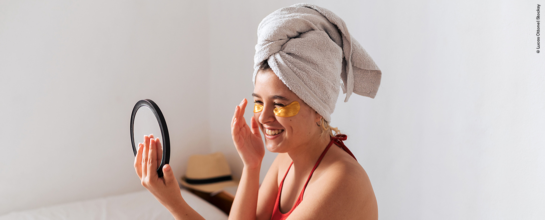 Frau sitzt mit Augenpads im Bett