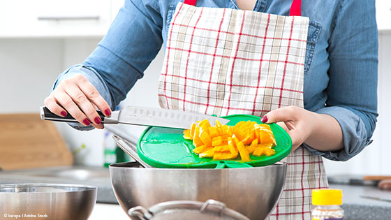 Frau gibt geschnittene Orangen in eine Schüssel