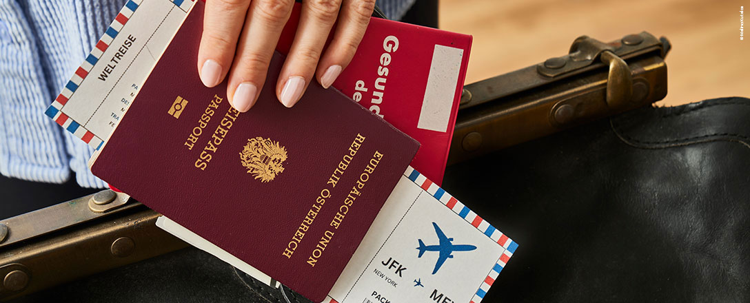 Frau hält Reisepass, Flugticket und Gesundheitspass in der Hand