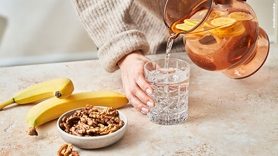Frau gießt Zitronenwasser in ein Wasserglas