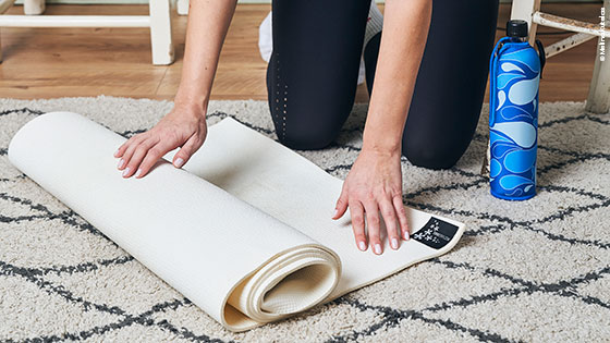 Frau rollt Sportmatte zuhause aus