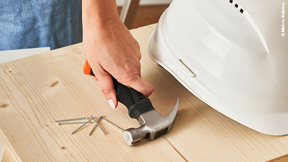 Shcutzhelm, Hammer und Nägel auf Holzbrett