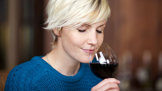 Frau riecht an Rotwein im Glas