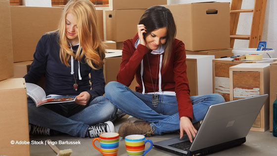 Zwei Frauen mit Laptop zwischen Umzugskartons