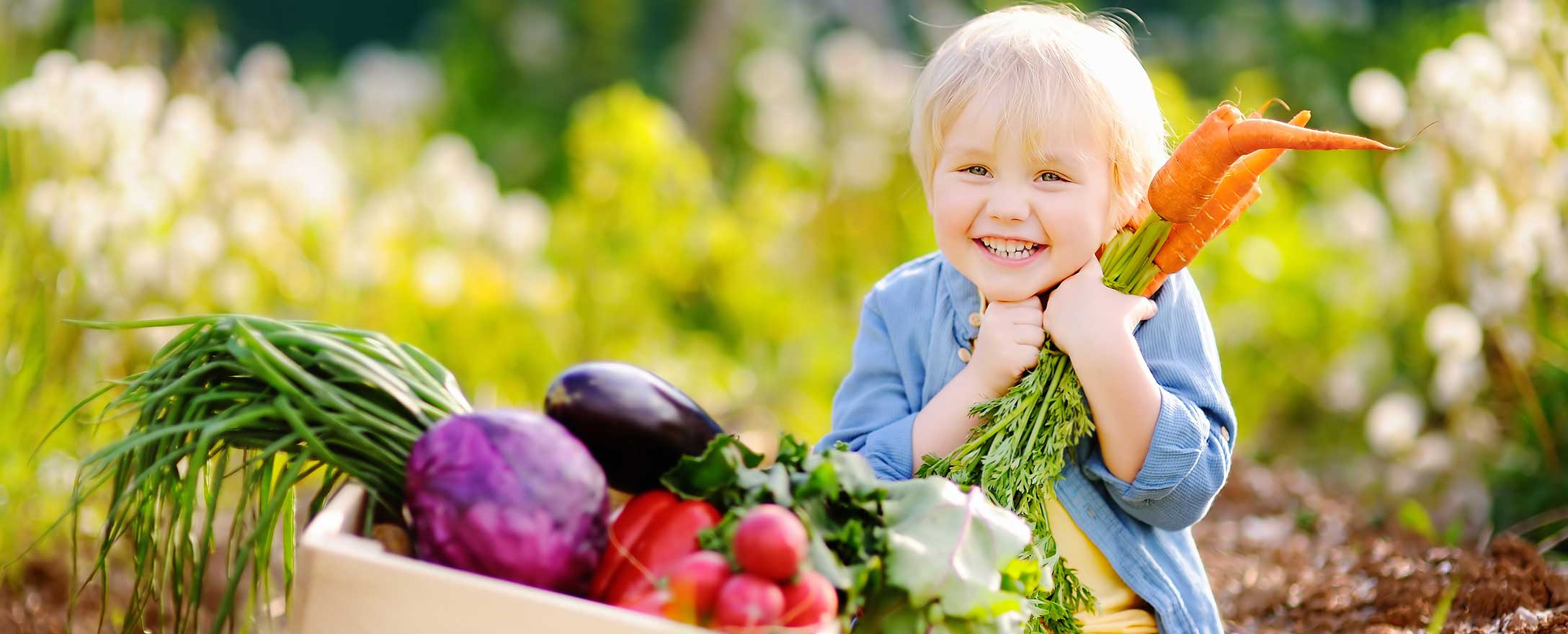 Kind lächelt mit Gemüse in der Hand