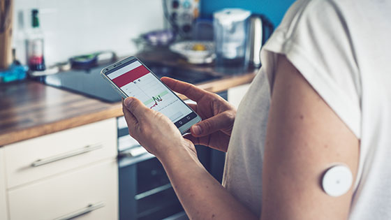 Person checkt Diabetes-App am Smartphone