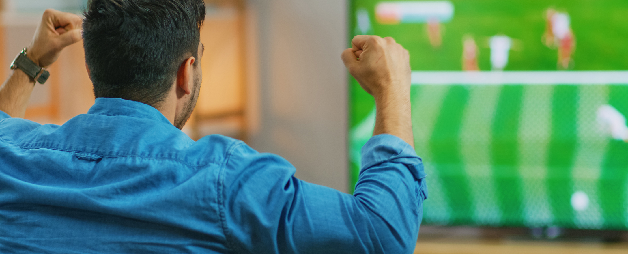 Mann jubelt beim Fußball anschauen im TV