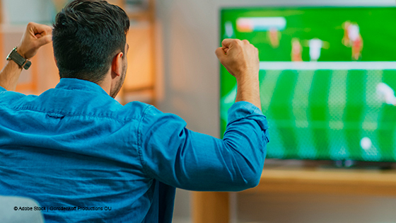 Mann jubelt beim Fußball anschauen im TV