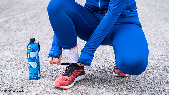 frau bindet joggingschuhe zu