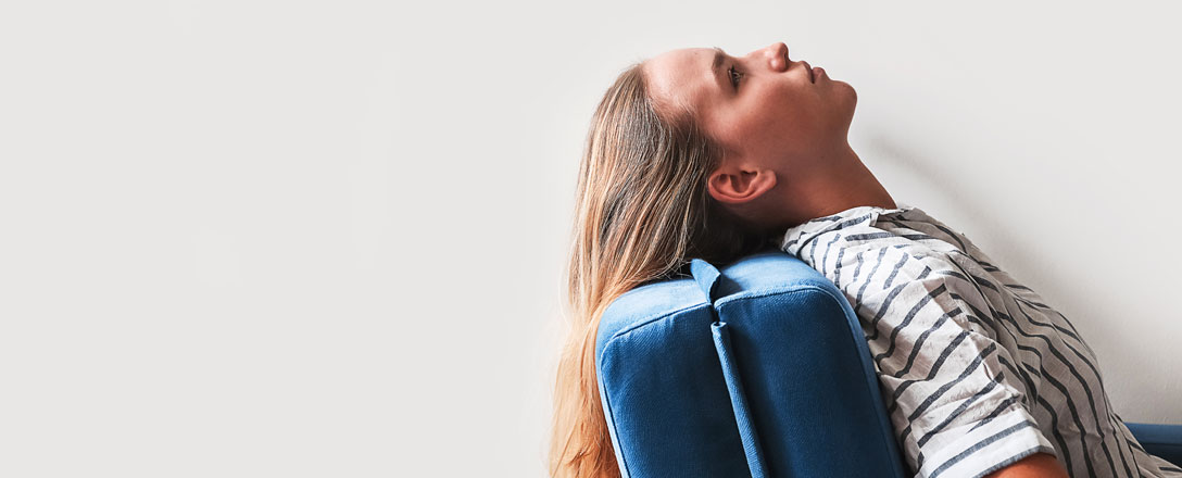 Frau sitzt auf einem blauen Stuhl und blickt an die Decke