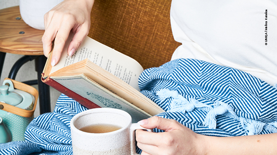 Frau genießt Zeit mit Buch und Tee