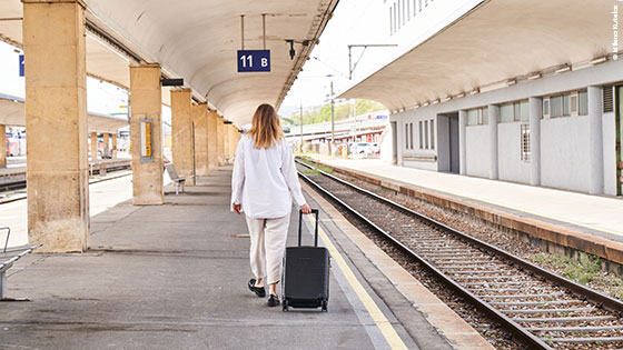 Person geht mit Rollkoffer Bahnsteig entlang