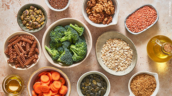 Essen in Schalen: Vollkornnudeln, Nüsse, Haferflocken, Brokkoli, Karotten und Öl in Flaschen