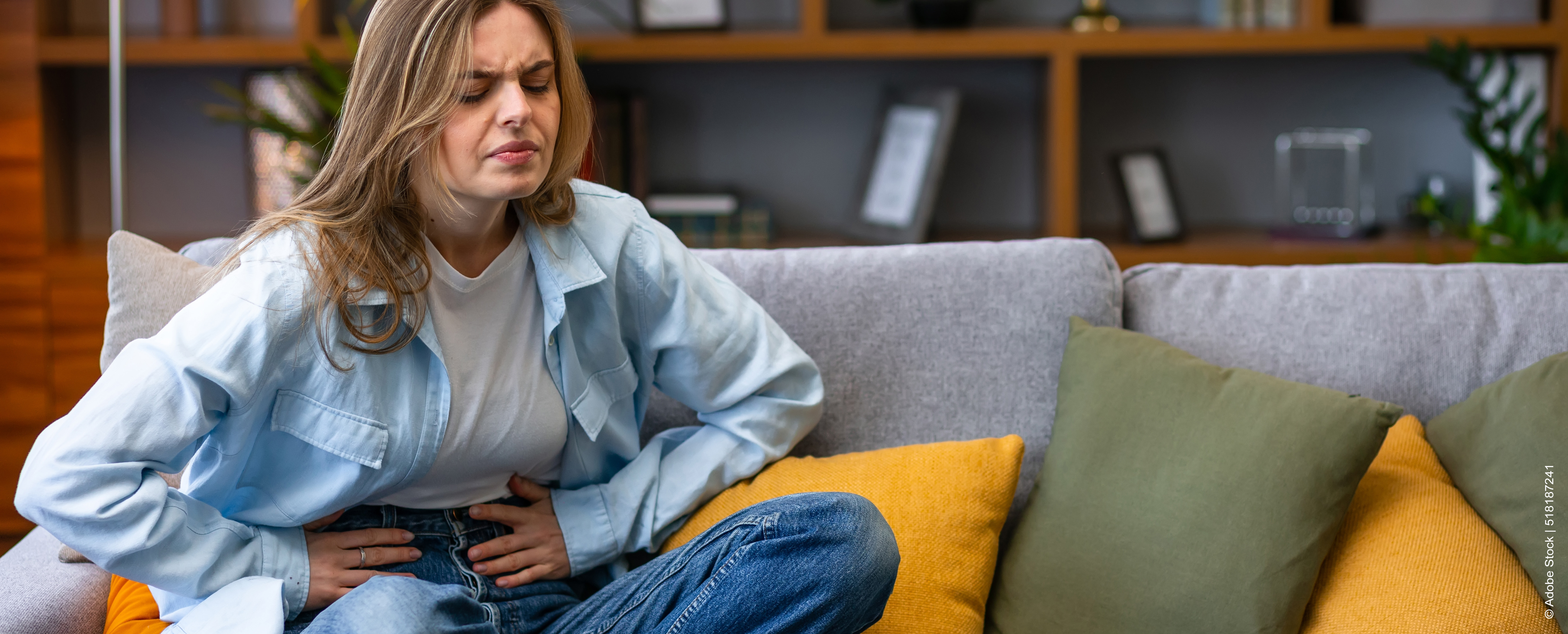 Sitzende Person hält sich Bauch