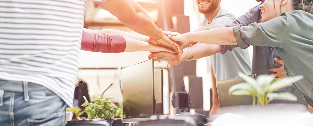 Menschen im Büro legen ihre Hände aufeinander