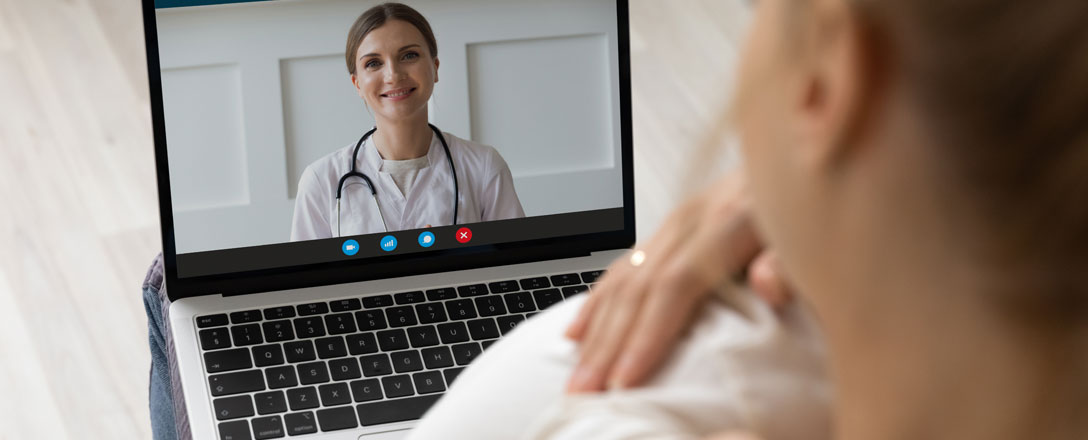 Frau mit Baby spricht am Laptop mit Ärztin