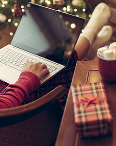 Frau mit Laptop und Weihnachtspackerl