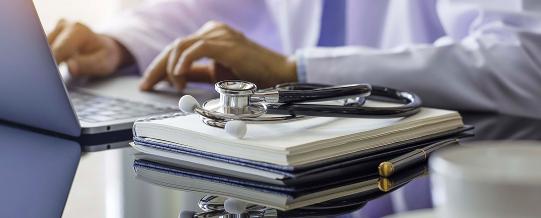 Ärztin am Laptop daneben Stethoskop