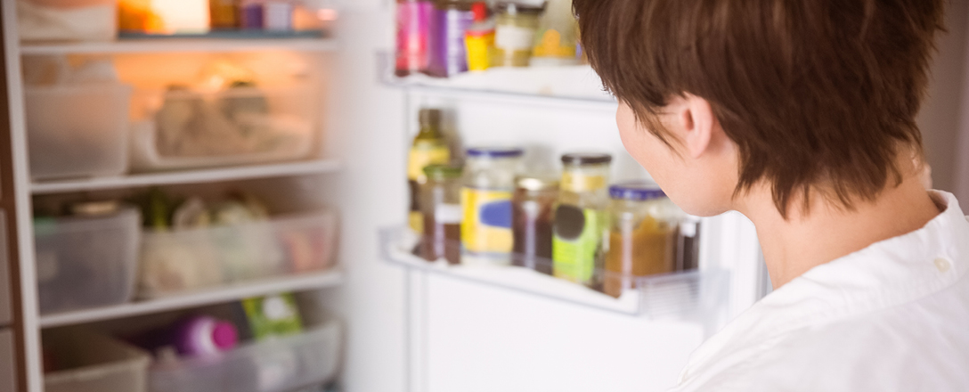 Frau schaut in den Kühlschrank