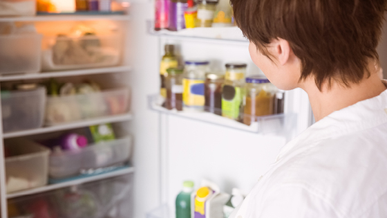 Frau schaut in den Kühlschrank