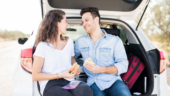 Frau und Mann essen im Kofferraum.