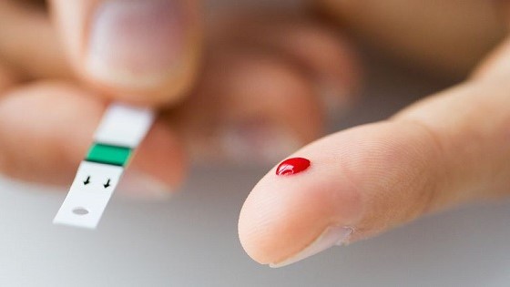 Finger mit Bluttropfen und Diabetes Teststreifen