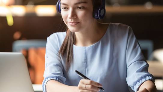 Junge Frau mit Kopfhörern vor Laptop