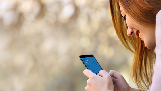 Frau öffnet myUNIQA App am Smartphone