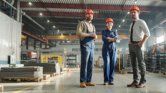 Drei Personen mit Helm in Werkshalle