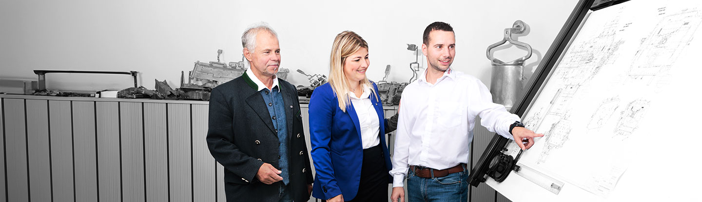 Drei Personen vor Planzeichnung