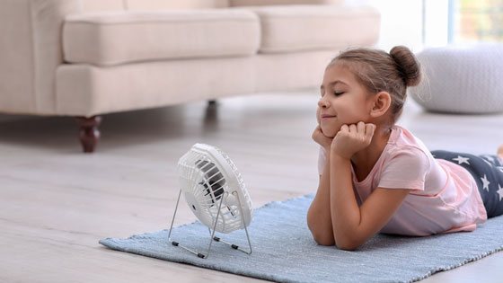 Kind liegt am Boden vor Ventilator