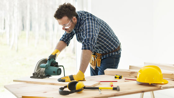 Mann schneidet Brett mit elektrischer Säge