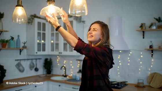 frau schraubt gluehbirne ein