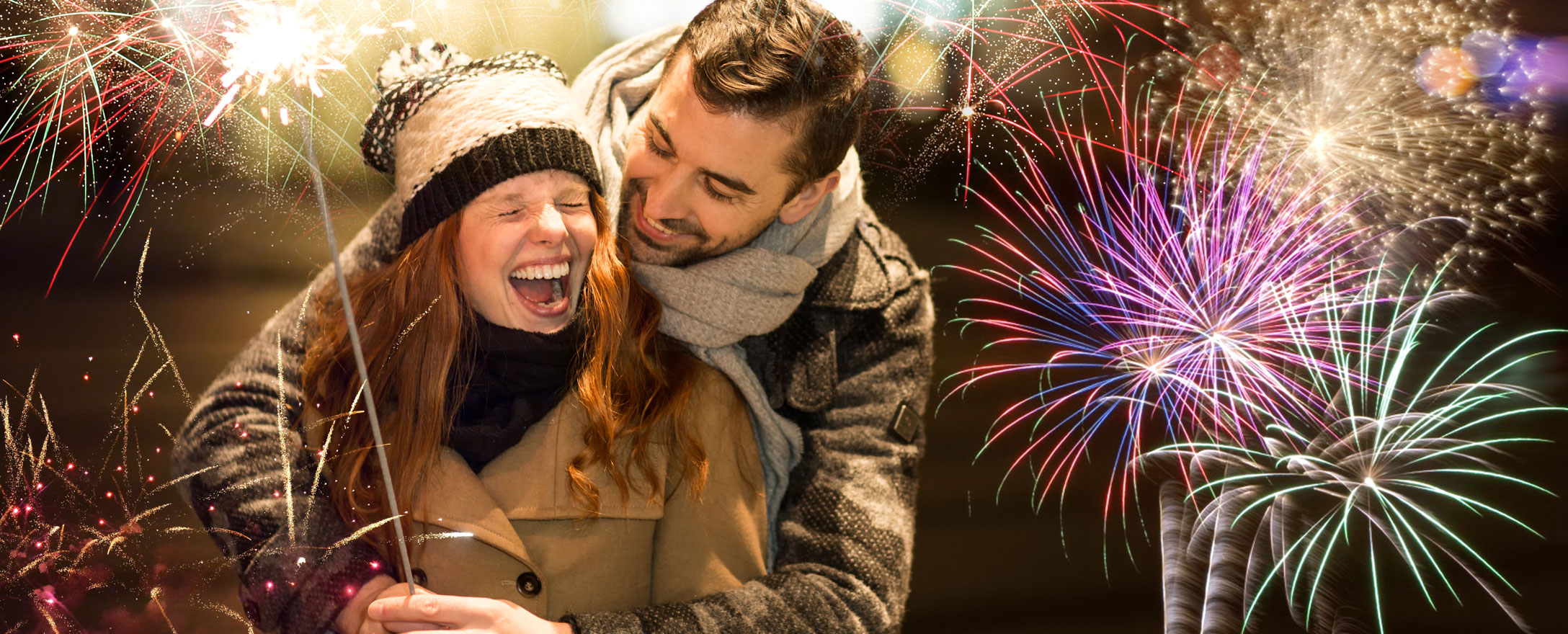 Junges Paar mit Silvesterfeuerwerk im Hintergrund