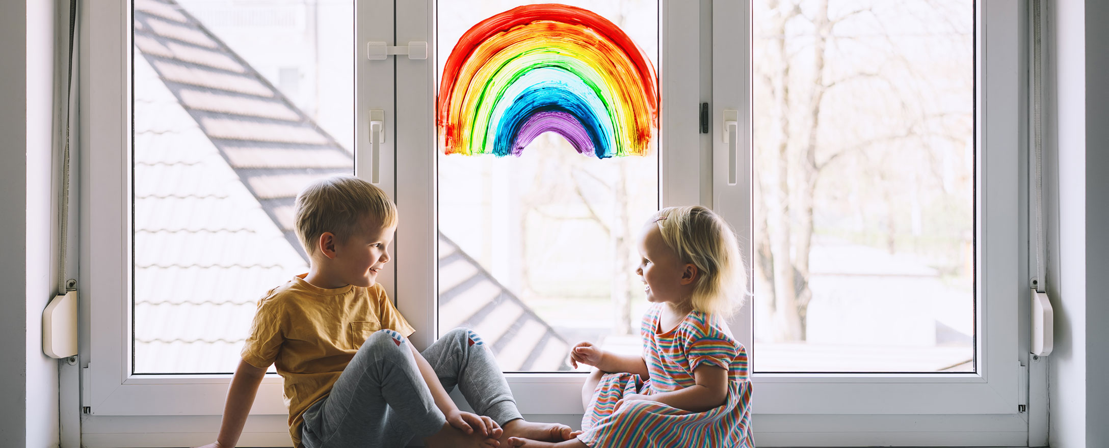 Kinder am Fenster mit Regenbogen